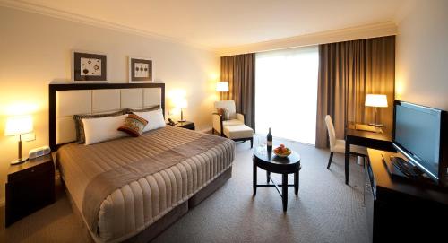 a hotel room with a bed and a flat screen tv at Century Inn in Traralgon