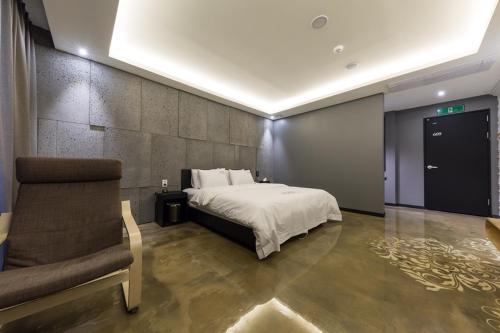 a bedroom with a bed and a couch and a chair at Anyang Boutique Hotel AMA in Anyang