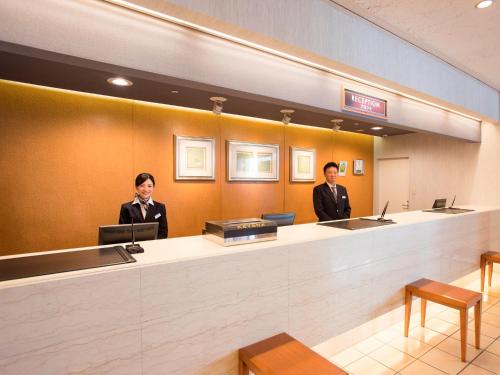 two men sitting at a reception desk in a hotel lobby at Alpico Plaza Hotel in Matsumoto