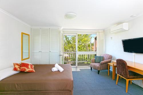 a bedroom with a bed and a desk and a television at Alloggio Bathurst in Bathurst