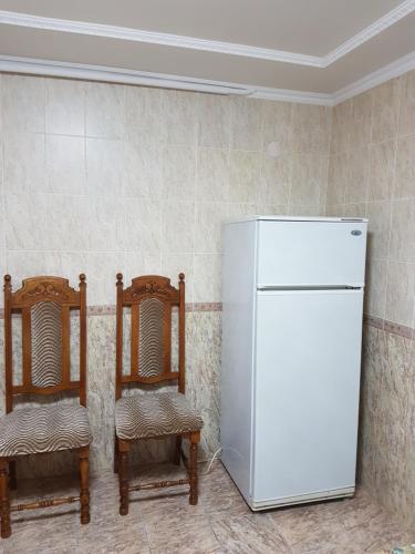 ピャチゴルスクにあるHoliday Home on Dzerzhinskogo 14のキッチン(椅子2脚、白い冷蔵庫付)