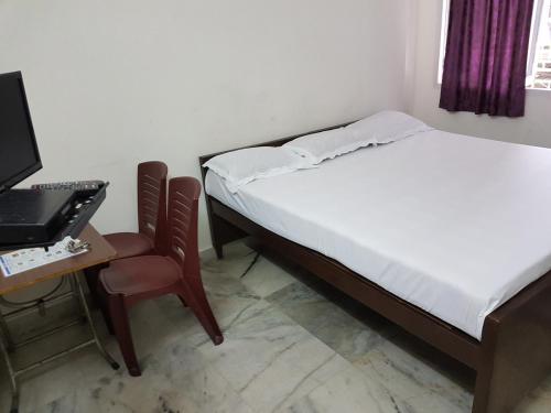 a bedroom with a bed and a desk with a computer at Georgian Inn in Kolkata