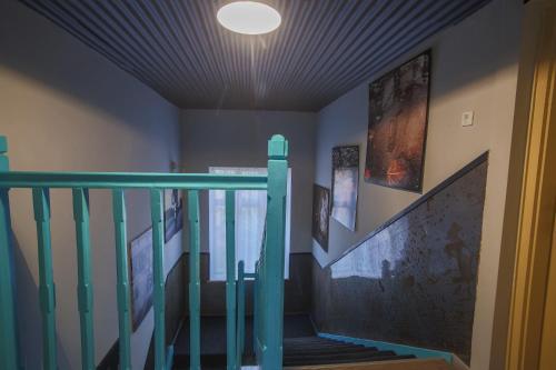 a hallway with a staircase with a green rail and paintings at Hotel Carpe Diem in Siófok
