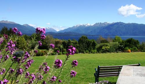 a bench in a field with mountains and purple flowers at High Leys Lodge in Te Anau