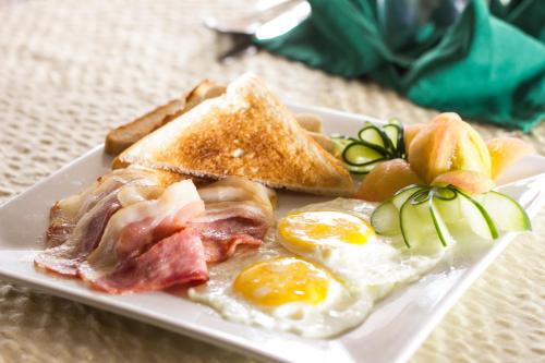 Un plato de desayuno con huevos, tocino y tostadas. en Tagaytay Country Hotel, en Tagaytay