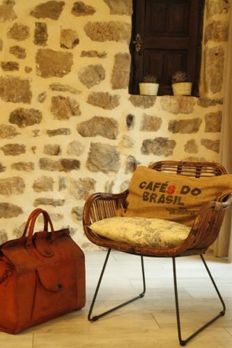 a wicker chair with a pillow and a suitcase at La Demeure des Maitres in Chirols