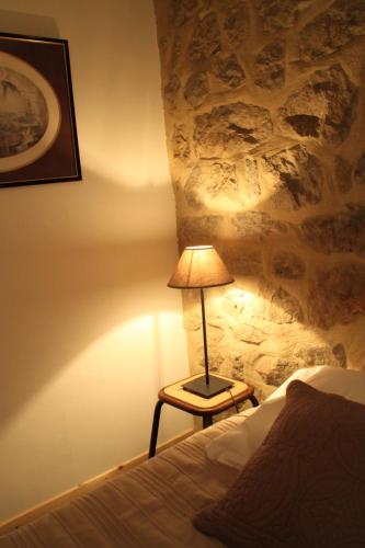 a lamp sitting on a table next to a bed at La Demeure des Maitres in Chirols