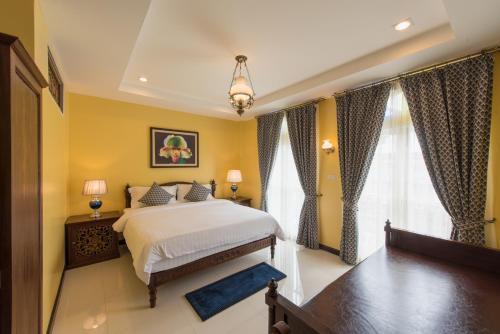 a bedroom with a bed with yellow walls and windows at The Velvet Orchid in Chiang Mai