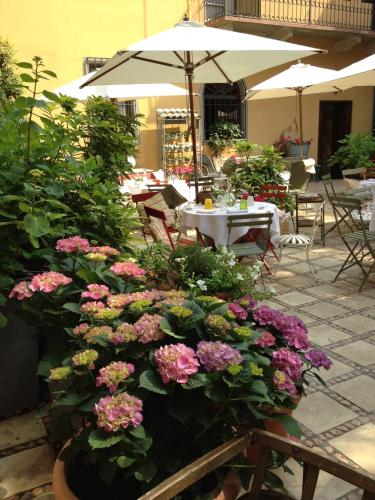 a garden with flowers and a table and an umbrella at Albergo Residence Perosi in Tortona