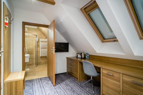 a bathroom with a shower and a desk with a chair at Hotel Górski in Białka Tatrzanska