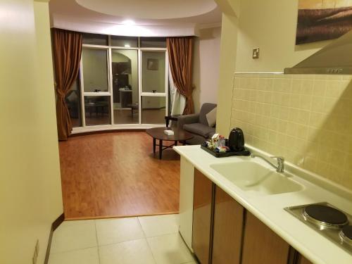 a kitchen with a sink and a living room at Travellerinn Serviced Apartment in Al Khobar