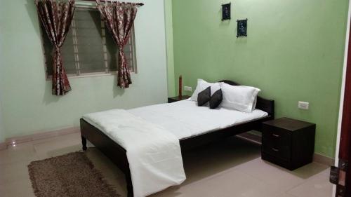 a bedroom with a bed with white sheets and a window at Tranquil Hospitality with Breakfast in Bhubaneshwar