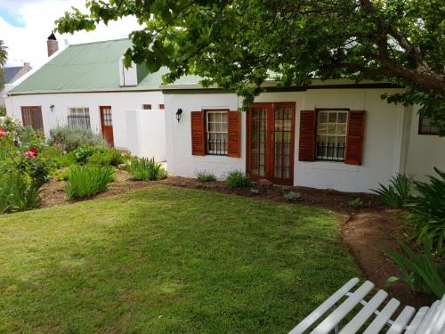 Casa blanca con techo verde y patio en Uniondale Manor Guesthouse, en Uniondale