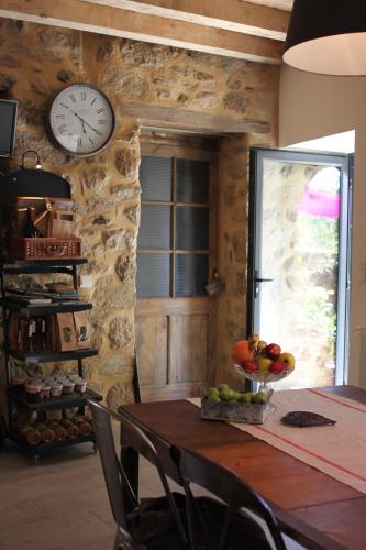 a dining room with a table and a clock on the wall at La Demeure des Maitres in Chirols