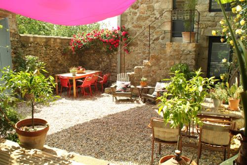 a patio with a table and chairs and plants at La Demeure des Maitres in Chirols