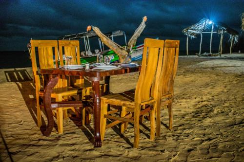 a wooden table and chairs on the beach at night at Omeesha Beach Hotel in Kalpitiya