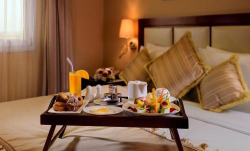 a tray of food on a bed in a hotel room at Coral Jubail Hotel in Al Jubail