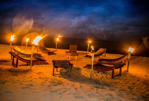a group of chairs and tables in the sand at night at Omeesha Beach Hotel in Kalpitiya