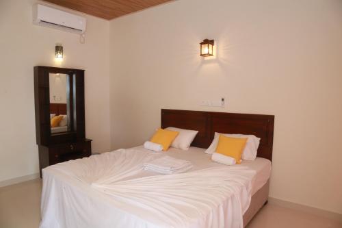 a bedroom with a bed with white and orange pillows at Serene Beach Hotel in Dickwella