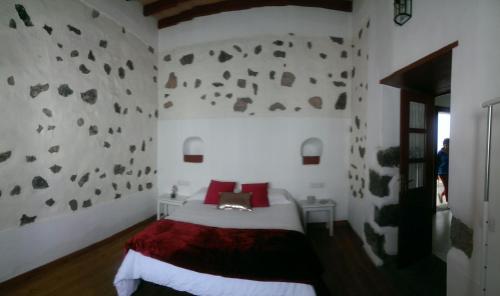 a bedroom with a bed and a rock wall at Casa Villalba in San Bartolomé