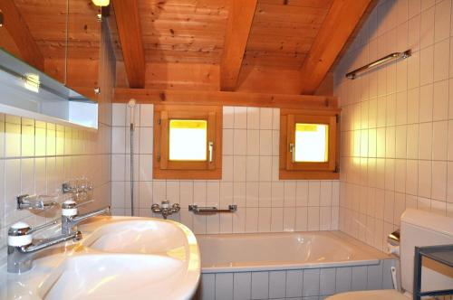 uma casa de banho com um lavatório e uma banheira em Suotchalchera 5 em Ftan