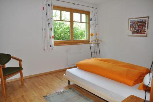 Zimmer mit einem Bett, einem Fenster und einem Stuhl in der Unterkunft Trü-Sura Nr. 4 in Scuol