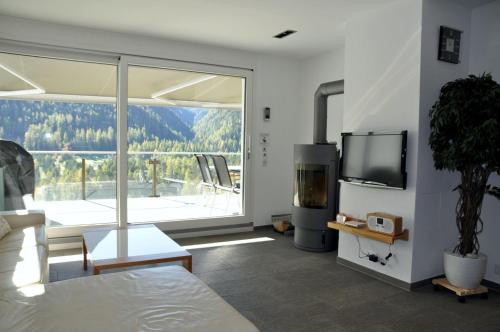 a living room with a tv and a large window at Chasa Miramunt 7 in Scuol