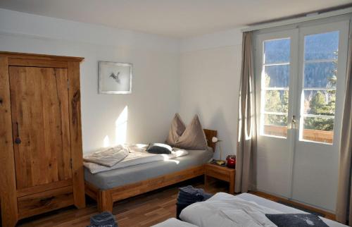 Schlafzimmer mit einem Bett und einem Fenster sowie einem Bett sidx sidx sidx in der Unterkunft Chalet Trü in Scuol