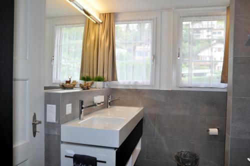 ein Badezimmer mit einem Waschbecken und zwei Fenstern in der Unterkunft Chalet Trü in Scuol