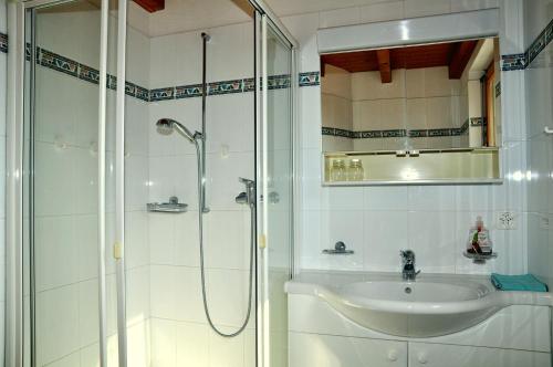 a white bathroom with a sink and a shower at Pütvia E6 in Scuol