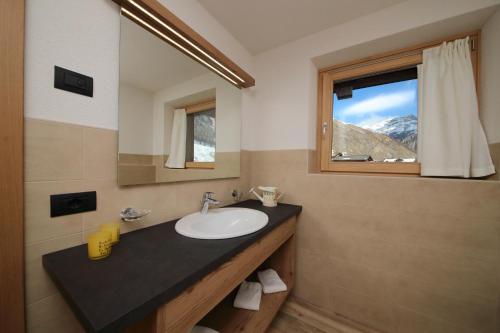 un bagno con lavandino, specchio e finestra di Reno - Happy Rentals a Livigno