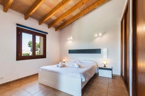 a white bedroom with a bed and a window at Can Mosca - Private Pool & Large Garden in Alcudia