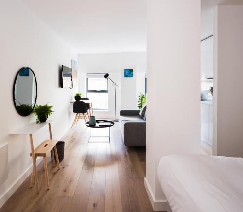a white bedroom with a couch and a table at Hiding Space Westgate Apartments in Bath