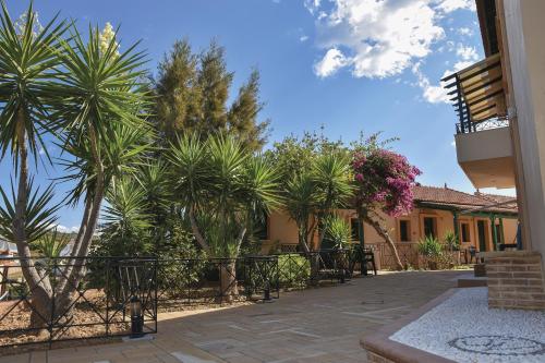 a courtyard with palm trees and a building at Sun Village Hotel Apartments in Megás Limniónas