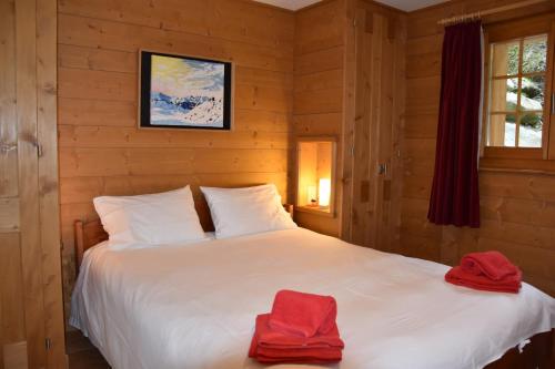 Un dormitorio con una cama blanca con toallas rojas. en Eclat de Soleil 023 en Verbier
