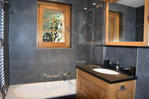 a bathroom with a sink and a shower and a tub at Eclat de Soleil 023 in Verbier