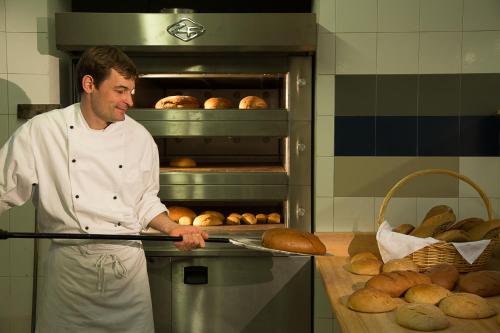 a man in a kitchen preparing bread in an oven at Sonnenhotel Adler Spa & Nature Adults only in Villandro