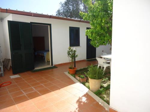 a white house with green doors and a patio at Villa Itaca in Sant'Isidoro
