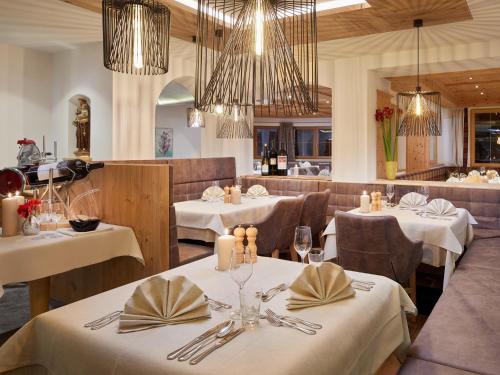 a restaurant with white tables and chairs and chandeliers at Hotel Tirol Fiss 4Sterne Superior in Fiss