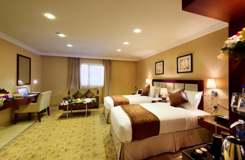 a hotel room with two beds and a desk at Coral Jubail Hotel in Al Jubail