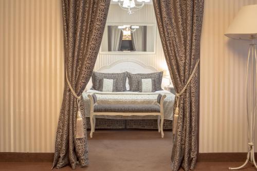 a bedroom with a bed and a chair with curtains at Hotel Chopin Business&SPA in Sochaczew