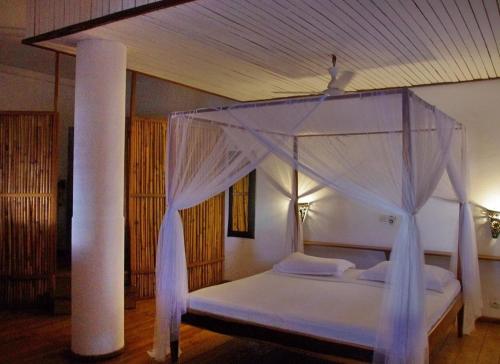 a bedroom with a white bed with a canopy at Nosy Lodge in Nosy Be