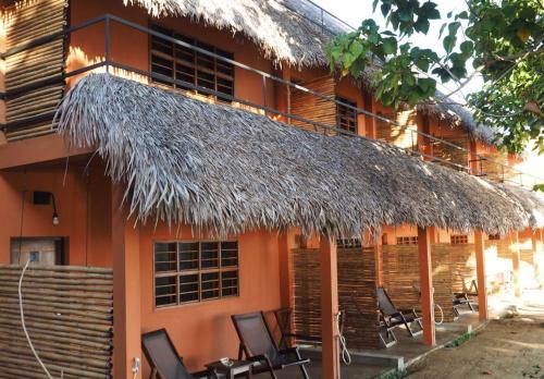 a building with chairs and a straw roof at Nosy Lodge in Nosy Be