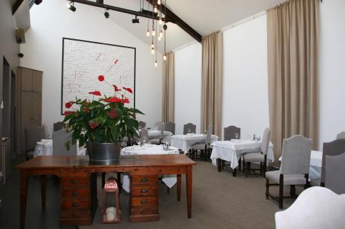 a dining room with tables with red flowers on a table at Les Loges de L'Atelier in Charlieu