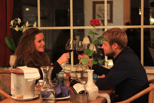 a man and woman sitting at a table with wine glasses at Chalet Hotel Adler in Kandersteg