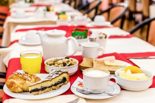 a table topped with plates of food and cups of coffee at Brunelleschi Hotel in Milan