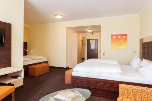 a hotel room with a large bed and a table at Best Western Hotel Augusta in Augsburg