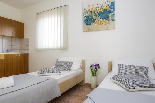 a bedroom with two beds and a kitchen at Lucky Luke Pool Apartments in Novalja