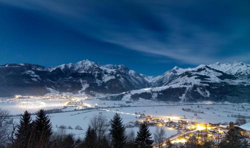 a town in the snow at night with mountains at Hotel Gasthof Mitteregger - BEST PLACE in town with summercard included in Kaprun
