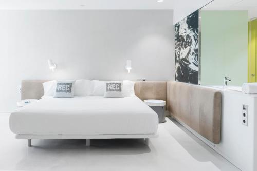 バルセロナにあるホテル レック バルセロナ　大人専用の白いベッドルーム(大きな白いベッド1台、バスタブ付)